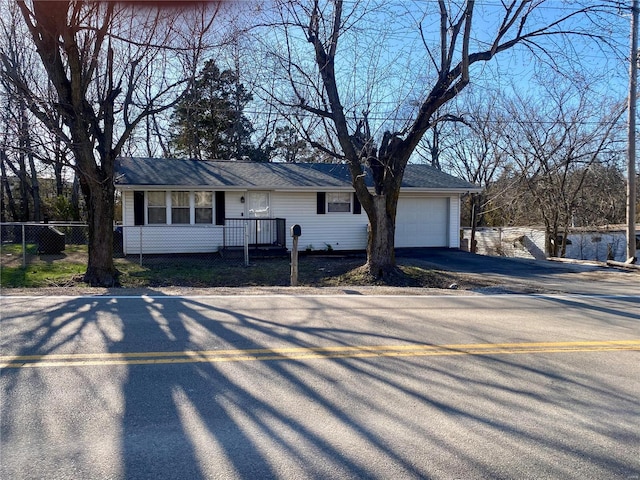 ranch-style home featuring aphalt driveway, a garage, and fence