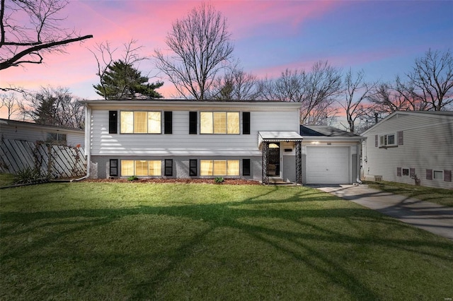 view of front of house with a yard, driveway, an attached garage, and fence