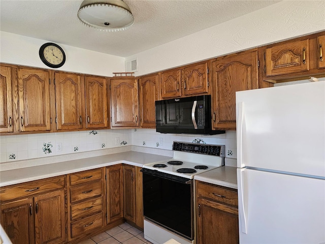 kitchen with brown cabinets, range with electric cooktop, black microwave, and freestanding refrigerator