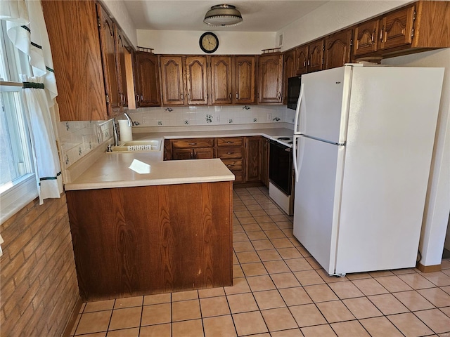 kitchen featuring light tile patterned floors, freestanding refrigerator, a sink, light countertops, and range with electric stovetop