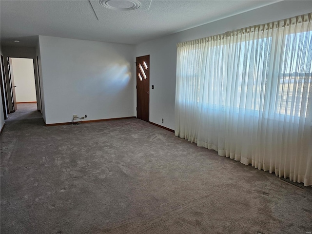 carpeted empty room with baseboards and a textured ceiling