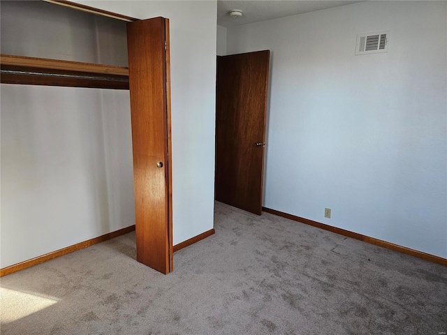 unfurnished bedroom with visible vents, baseboards, a closet, and carpet flooring