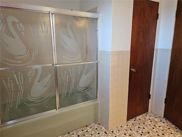 bathroom with tile walls and enclosed tub / shower combo