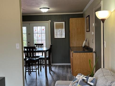 dining room featuring a textured ceiling, dark wood-style flooring, and crown molding