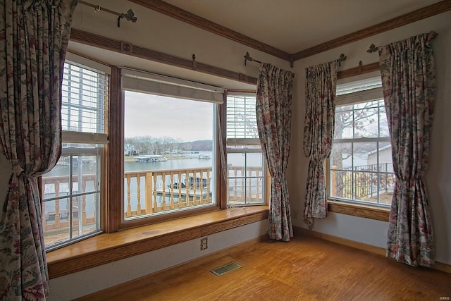 dining room featuring visible vents, plenty of natural light, crown molding, and a water view