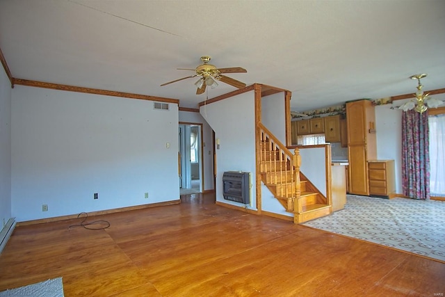 unfurnished living room featuring heating unit, visible vents, ornamental molding, stairs, and ceiling fan