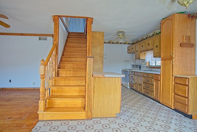 kitchen featuring visible vents, ceiling fan, light countertops, electric range oven, and a sink