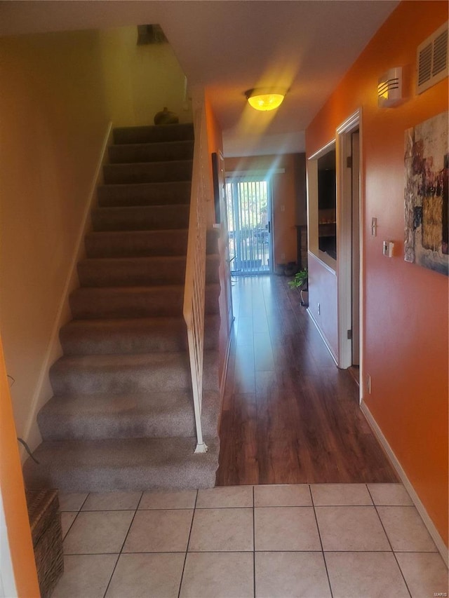 stairs with tile patterned flooring, visible vents, and baseboards