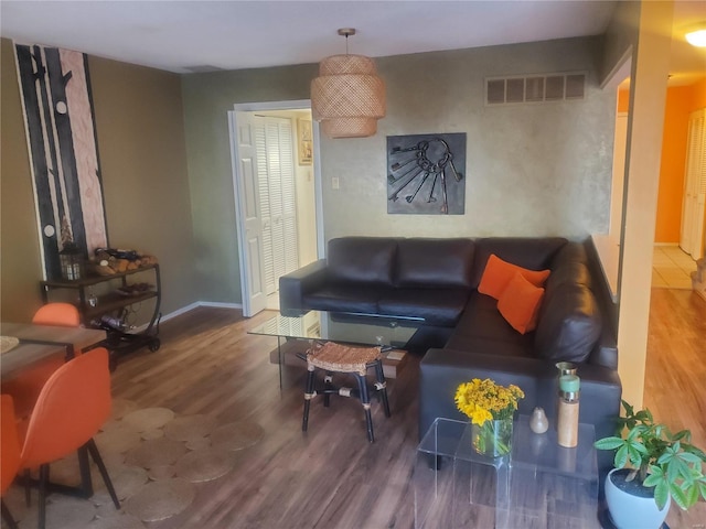 living room featuring baseboards, visible vents, and wood finished floors