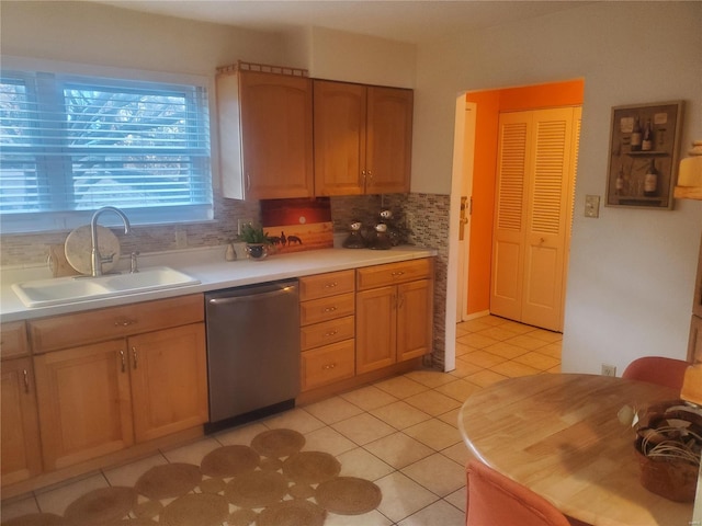 kitchen with light tile patterned floors, tasteful backsplash, light countertops, a sink, and dishwasher