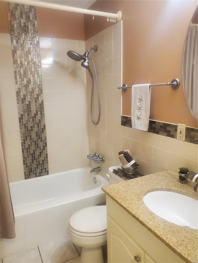 bathroom with toilet, tile patterned floors,  shower combination, vanity, and tile walls