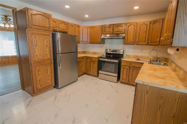 kitchen with marble finish floor, appliances with stainless steel finishes, brown cabinets, and a sink