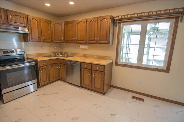 kitchen with visible vents, brown cabinets, marble finish floor, stainless steel appliances, and under cabinet range hood