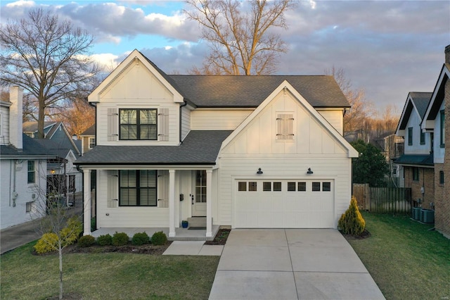 modern farmhouse with a garage, covered porch, board and batten siding, and fence