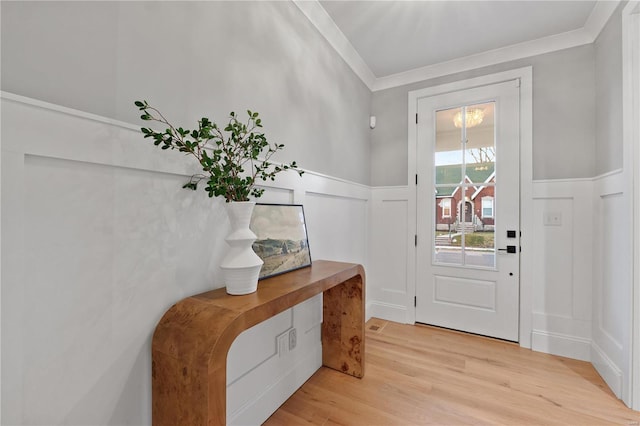 entryway featuring a decorative wall, a wainscoted wall, light wood finished floors, and ornamental molding