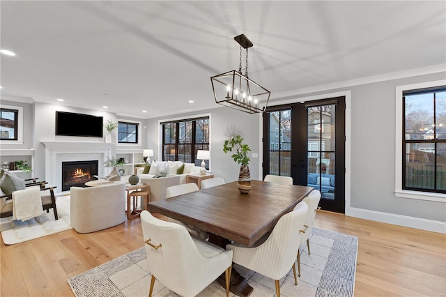 dining room with crown molding, light wood-style floors, and a premium fireplace