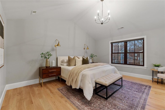 bedroom featuring baseboards, visible vents, light wood finished floors, lofted ceiling, and a chandelier