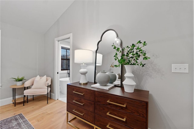 sitting room featuring baseboards, light wood-style floors, and vaulted ceiling