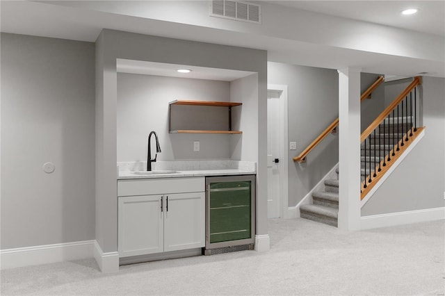 bar with visible vents, beverage cooler, a sink, light colored carpet, and stairs