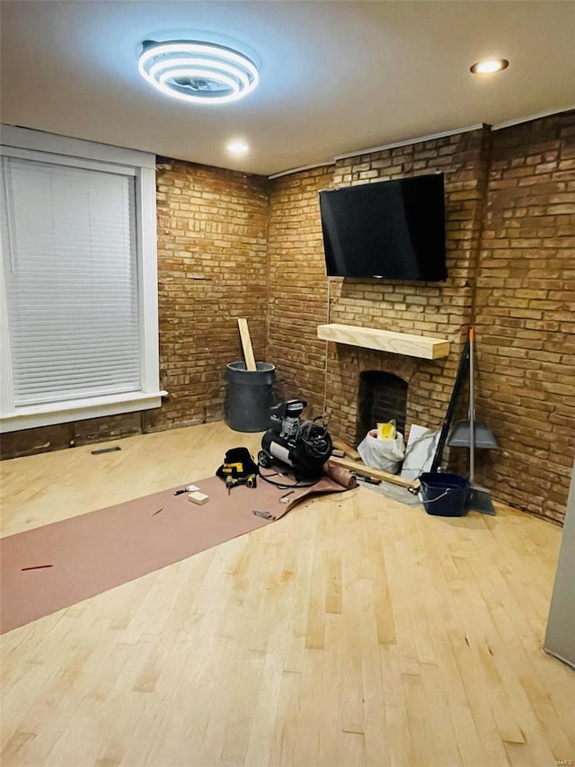 workout room featuring brick wall, a fireplace, and wood finished floors