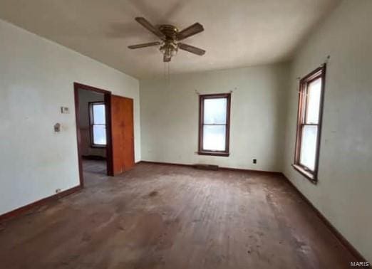 empty room featuring ceiling fan, baseboards, a wealth of natural light, and wood finished floors