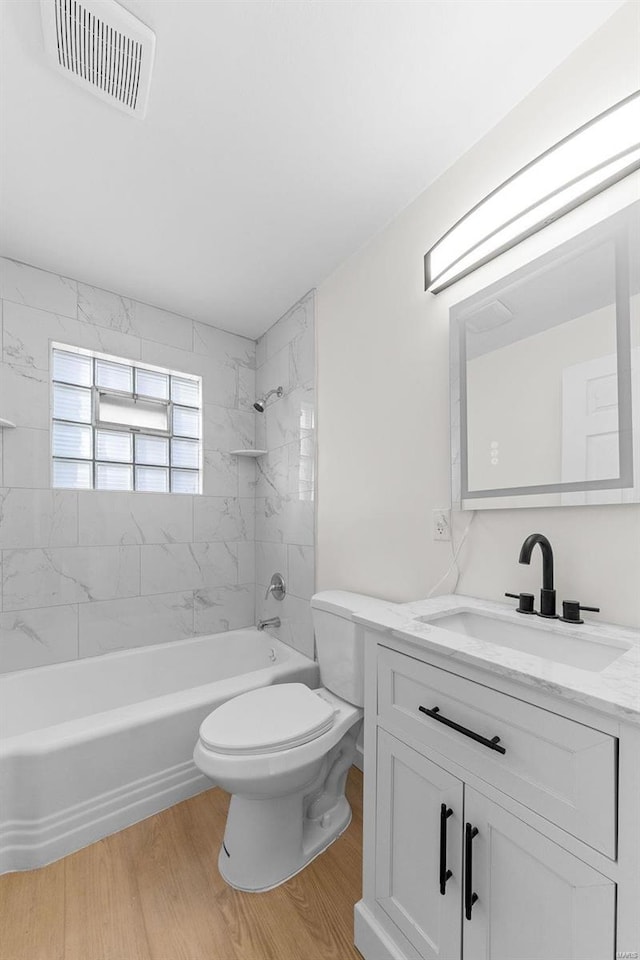 bathroom with visible vents, toilet, vanity, wood finished floors, and washtub / shower combination