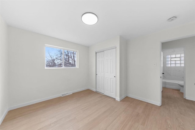 unfurnished bedroom with visible vents, light wood-style floors, a closet, and baseboards