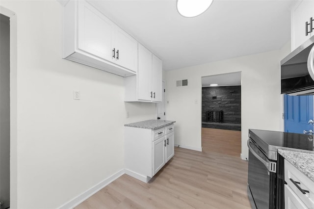 kitchen with light stone counters, baseboards, white cabinets, appliances with stainless steel finishes, and light wood-type flooring