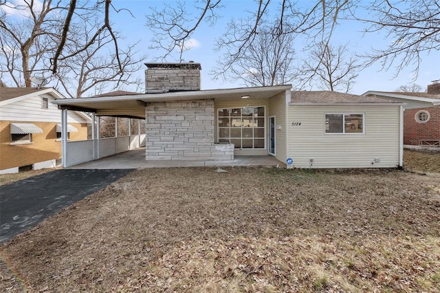 view of front facade featuring a carport, a chimney, and aphalt driveway