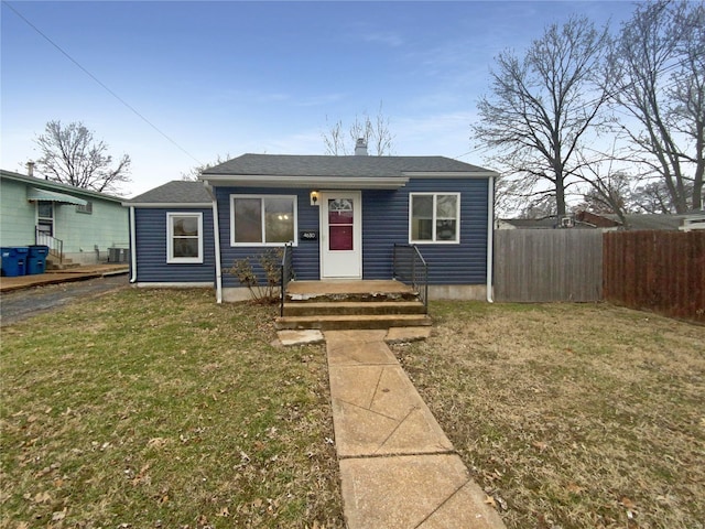 bungalow-style home featuring central air condition unit, a front lawn, and fence