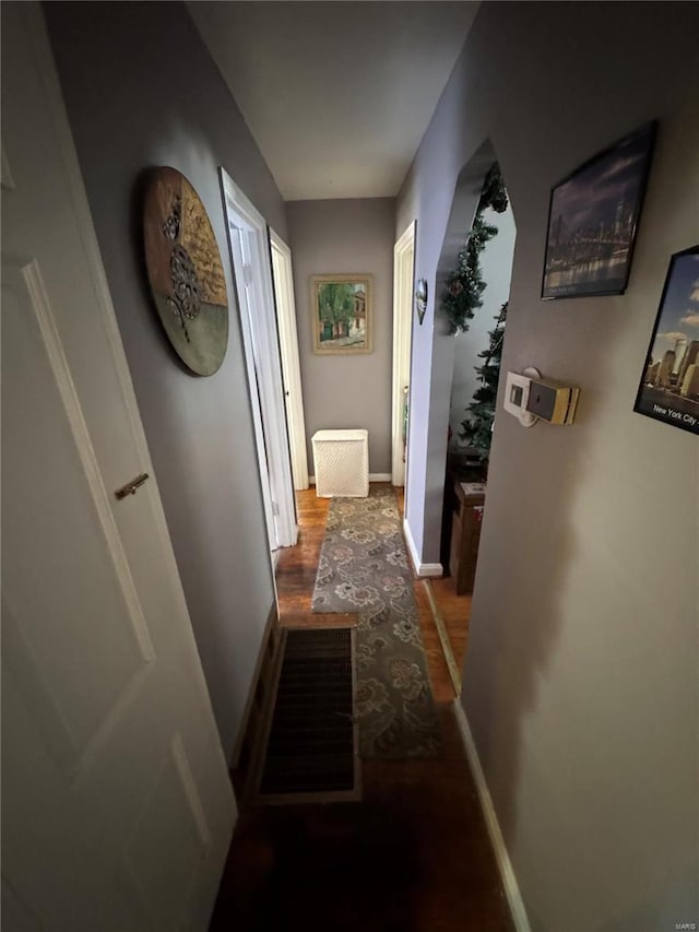 corridor featuring baseboards and wood finished floors