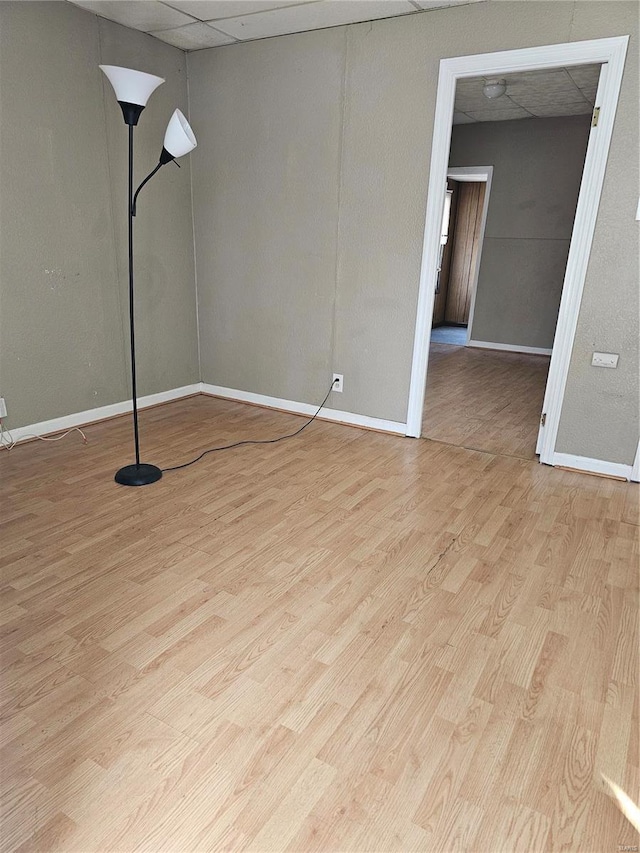 spare room with wood finished floors, baseboards, and a drop ceiling