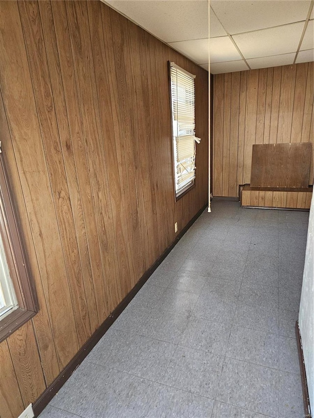 unfurnished room featuring tile patterned floors, wood walls, and a paneled ceiling