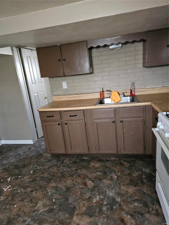 kitchen with white range with gas cooktop, light countertops, and a sink