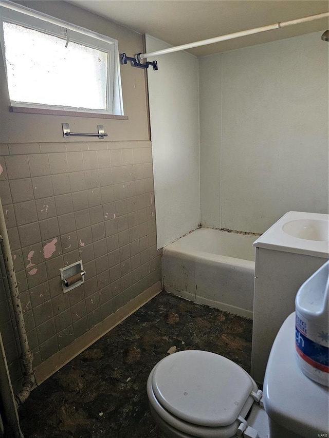 full bathroom featuring toilet, tile walls, and washtub / shower combination