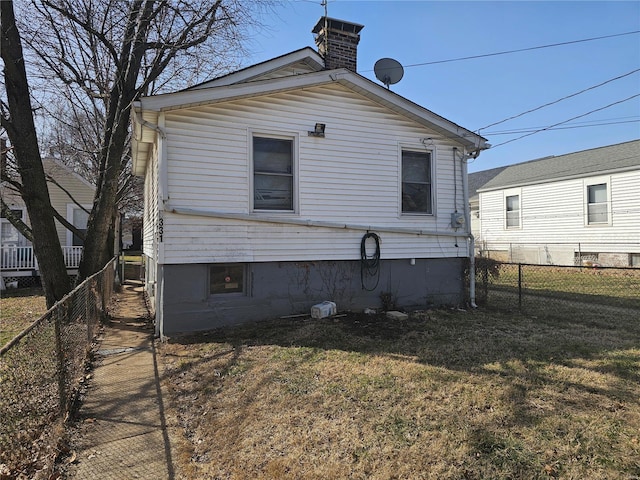 rear view of house with a yard, a fenced backyard, and a chimney