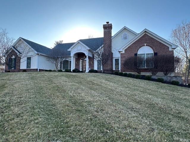 view of front of home featuring a front lawn, brick siding, and a chimney