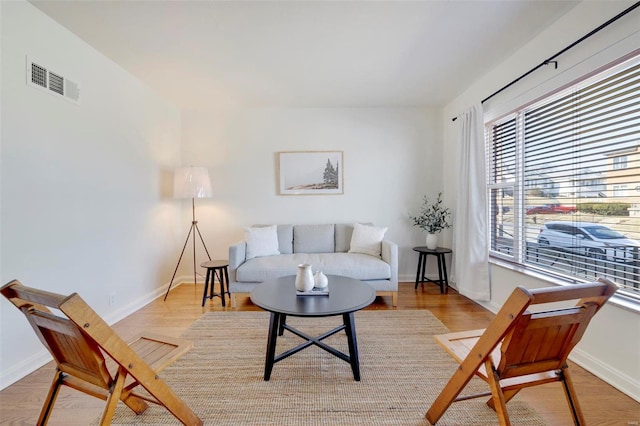 living area with visible vents, baseboards, and wood finished floors