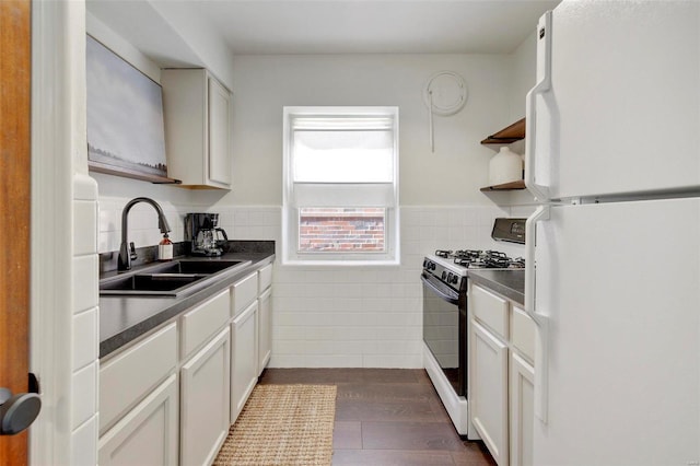 kitchen featuring open shelves, a sink, freestanding refrigerator, gas stove, and tile walls