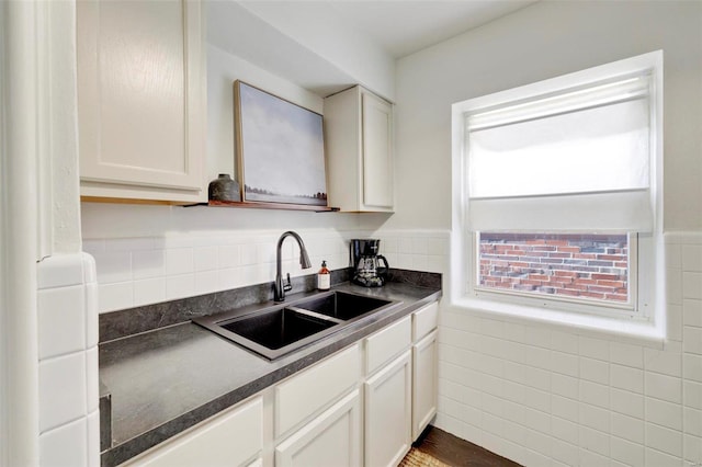 kitchen featuring dark countertops, white cabinets, and a sink