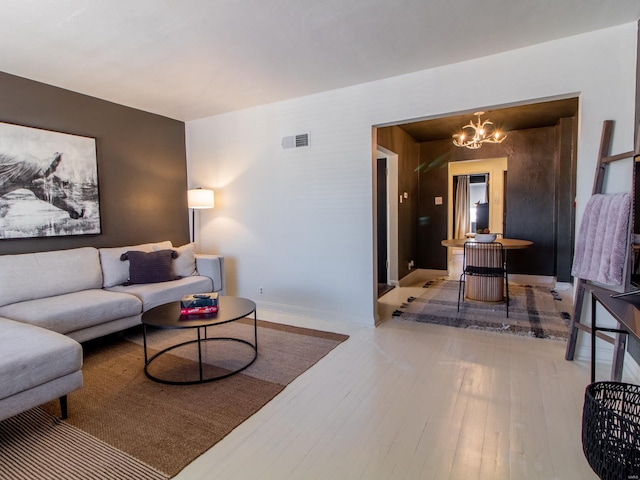 living area with a chandelier, visible vents, baseboards, and hardwood / wood-style floors