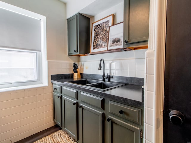 kitchen with a sink, dark countertops, and tile walls