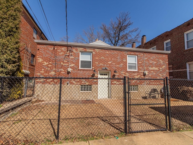 back of property featuring fence, brick siding, a chimney, and a gate