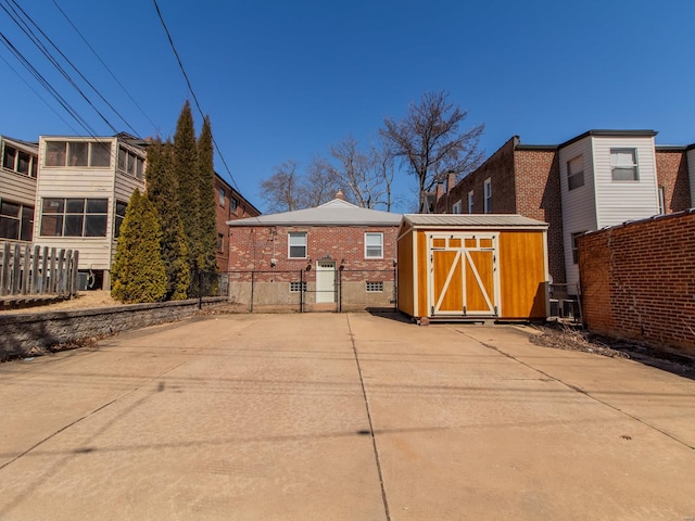 rear view of house with an outbuilding, fence, brick siding, and a shed