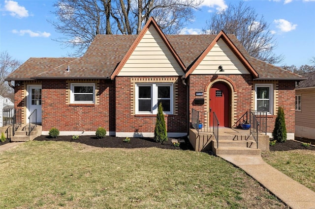 view of front of home with brick siding, a shingled roof, and a front yard