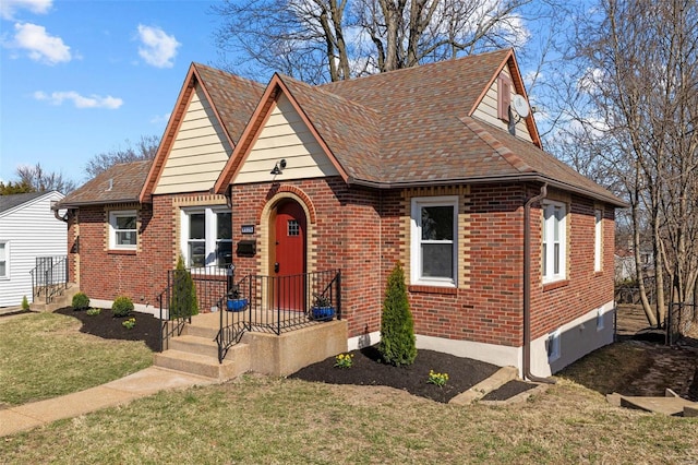 view of front of home with brick siding, a front yard, and roof with shingles