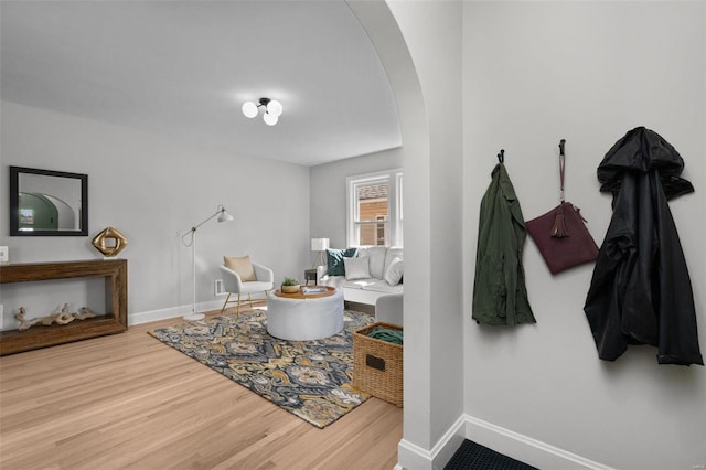 living area featuring wood finished floors, arched walkways, and baseboards