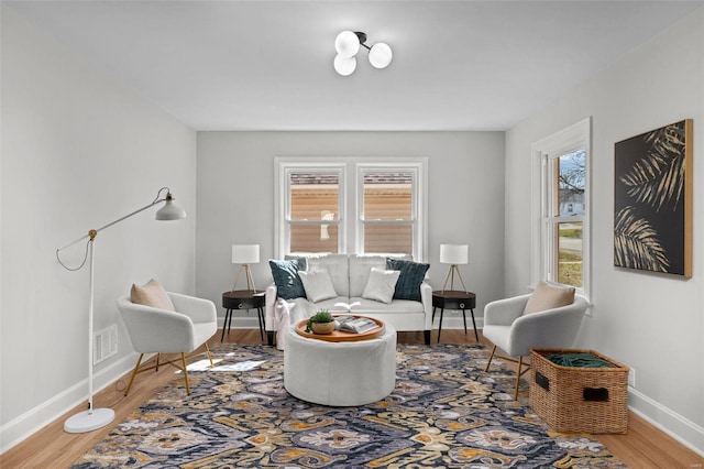 living area featuring visible vents, wood finished floors, and baseboards