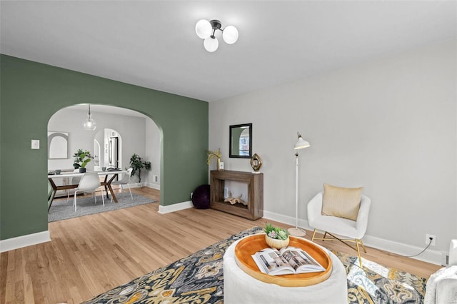 living room featuring baseboards, arched walkways, and wood finished floors