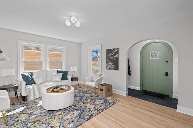 living room with arched walkways, baseboards, and wood finished floors